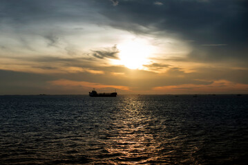 Sunset over the sea with shadows of industrial ships