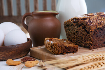 Homemade rye bread with raisins, milk, eggs and wheat ears on the table. Selective focus.