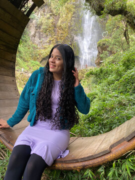 GIRL WITH BLACK CURLY HAIR WITH BACK TO A WATERFALL