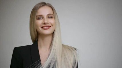Slow motion of the flying hair of a charming blonde. Grey background.
