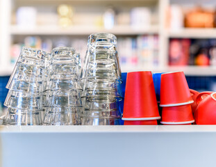 Coffee cups and water glasses on top of a coffee machine at a brightly lit café