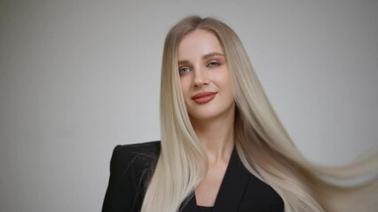 Slow motion of the flying hair of a charming blonde. Grey background.