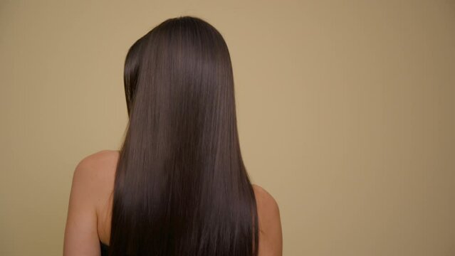 Slow motion of the long hair of a cute brunette girl. Yellow background.