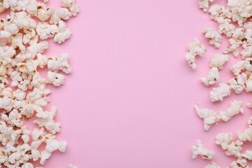 Tasty popcorn scattered on pink background, flat lay. Space for text