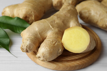 Fresh ginger with leaves on white wooden table, closeup