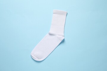 One white sock on light blue background, top view