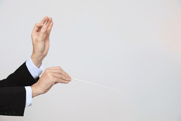 Professional conductor with baton on light grey background, closeup. Space for text