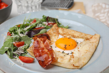 Delicious crepe with egg on plate, closeup. Breton galette