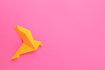 Beautiful orange origami bird on pink background, top view. Space for text