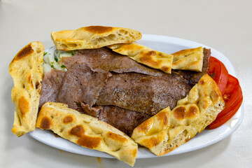 Turkish and Arabic Traditional Ramadan doner kebab with tasty tomato sauce and rice or turkish pilav in white plate on wood table background. ( Pilav ustu doner)