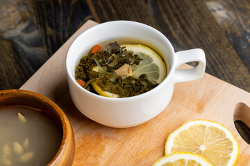 Green tea in a white cup during its brewing