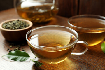 Fresh green tea in glass cups and leaves on wooden table