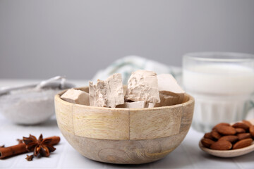 Wooden bowl with compressed yeast on white tiled table, closeup