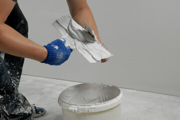 Professional worker putting plaster on putty knife indoors, closeup