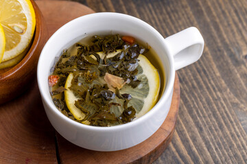 Green tea in a white cup during its brewing