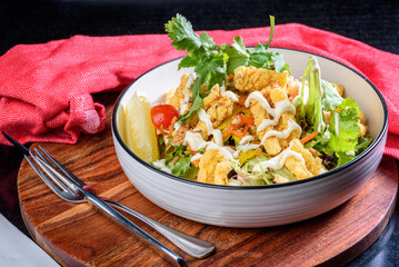 A plate of crispy Calamari Salad with lettuce, radish, lemon and avocado.