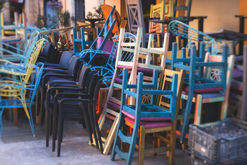 Chairs piled up in empty cafe, the end of touristic season, closed restaurant in the european streets, bad season, end of working hours, seats stacked in after hours, restaurant went bust bankrupt