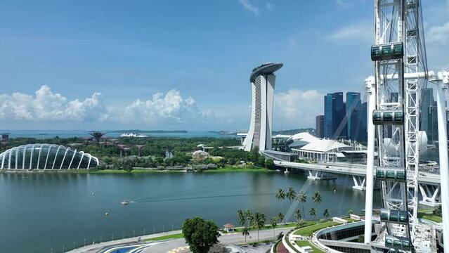 Drone orbiting shot of Singapore Flyer Eye, Marina Promenade, with Marina Bay Sands and Singapore and city in background.