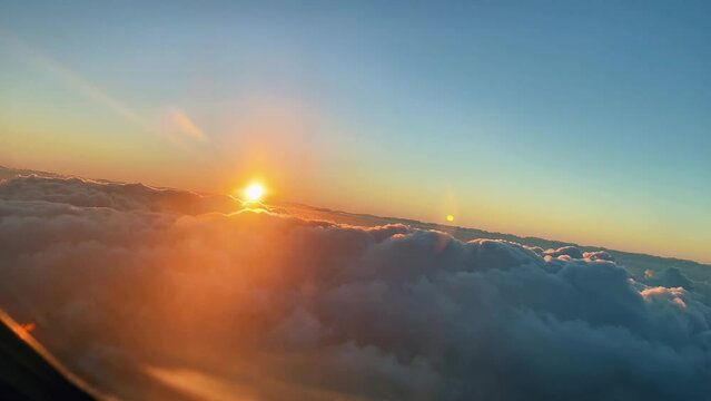 Front view of an airplane turning above the clouds at sunset. Pilot's view