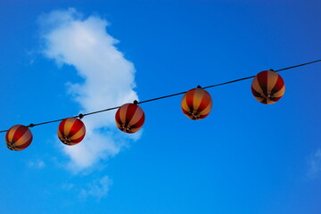 日本の夏祭りに使われる赤い提灯が飾り付けられている風景と青空