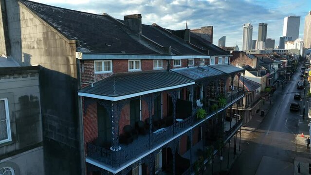 French Quarter homes with ironwork gallery balcony and New Orleans skyline. St. Louis Cathedral and Huey P Long bridge over Mississippi River.