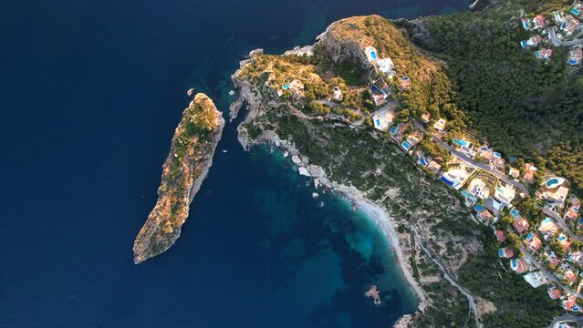 Aerial Birds Eye View Over Clifftop Villas Along Javea Coastline With Tilt Up Reveal Of Golden Sunset On Horizon