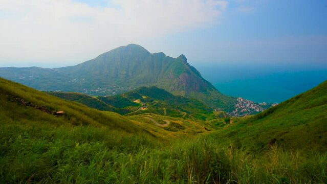 A village in the valley. The winding mountain road and the sea in the distance. Ruifang District, New Taipei City, Taiwan.  Time-lapse photography