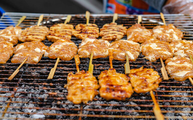 Milk marinated pork skewered on bamboo grills over charcoal for sale along the sidewalk in Bangkok, Thailand.