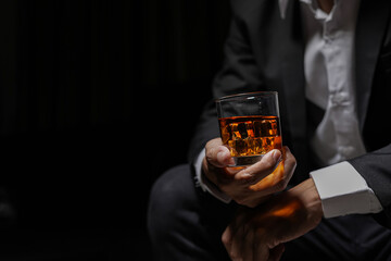 Closeup businessmen holding a glass of whiskey - obrazy, fototapety, plakaty