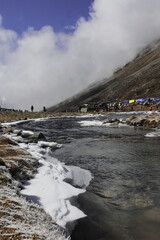 scenic mountain landscape, frozen stream and alpine valley of zero point surrounded by snowcapped himalaya mountains in north sikkim, india