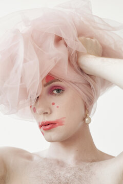 Medium close up portrait of feminine young man wearing modern make up posing with tulle headwear