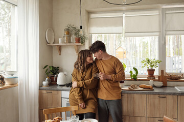 Married couple in love wearing casual outfit spending time together standing in modern kitchen horizontal shot