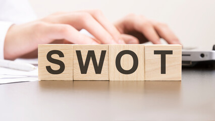 man made word SWOT with wood blocks on the background of the office table. selective focus. business concept.