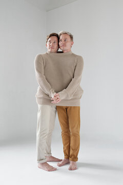 Contemporary shot of identical brothers standing together like siamese twins