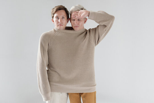 Medium shot of Caucasian twin brothers standing together in one big sweater