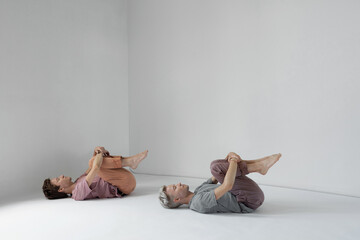 Horizontal shot of two young men lying on floor in identical poses with eyes closed
