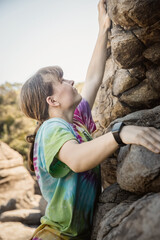 Fototapeta premium young teen girl climbing bouldering on natural cliff, outdoor bouldering activity. High quality photo