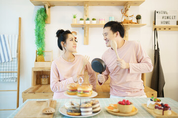 Obraz na płótnie Canvas Happy young couple cooks a breakfast together in kitchen, romantic Asian young couple cooking a breakfast in the morning.