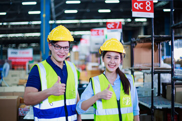 Asian female and male workers show thumb up signal at building construction material store manufacturing warehouse, packaging products, shipping export logistics warehouse.