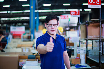 Asian male worker show thumb up signal at building construction material store manufacturing warehouse, packaging products, shipping export logistics warehouse.