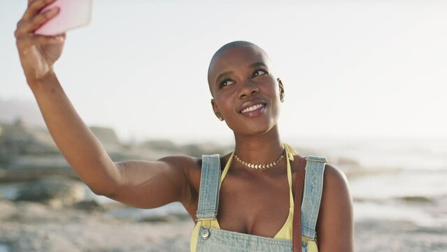 Black woman, selfie and beach with a smile for travel, vacation and freedom while holding phone for social media content or influencer blog. Bald African female with beauty outdoor on ocean holiday