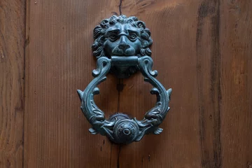 Fototapeten Un heurtoir de porte en fer forgé de style gothique, medieval et Renaissance sur une porte en bois dans la ville de Sienne en Italie © Obatala-photography