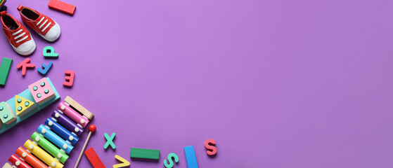 Set of children's toys with booties on purple background with space for text