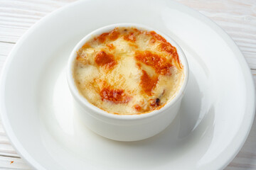 Baked julienne with mushrooms and cheese on top on white plate