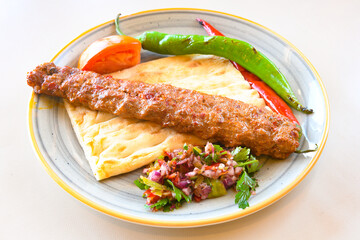 Grilled Turkish Adana, Urfa  Kebab with grilled vegetables, onion and rice on plate. Adana durum.