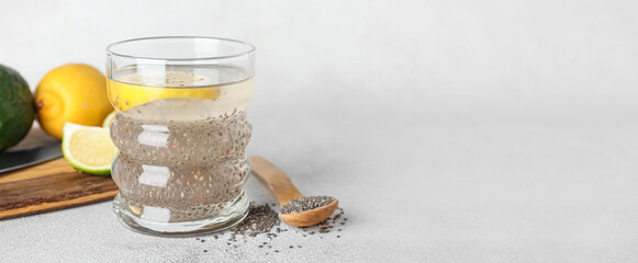 Glass of water with chia seeds and citrus fruits on light background with space for text