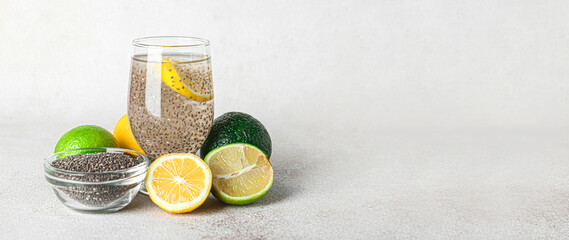 Glass of water with chia seeds and citrus fruits on light background with space for text