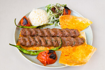 Grilled Turkish Adana, Urfa  Kebab with grilled vegetables, onion and rice on plate. Adana durum.