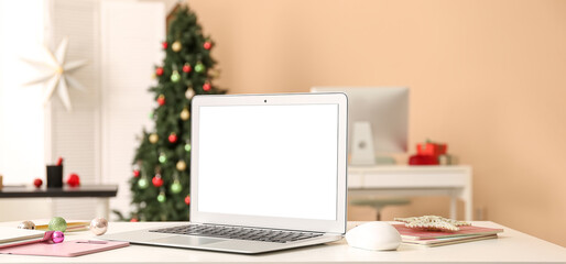 Modern laptop on table in office decorated for Christmas