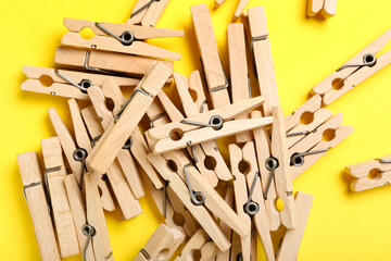 Heap of wooden clothespins on yellow background, closeup